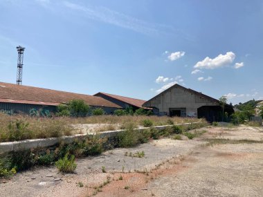 Fransa 'da terk edilmiş demiryolu tersanesi, paslı raylar, terkedilmiş vagonlar ve aşırı gelişmiş bitkiler, endüstriyel mirasın çürümesini yansıtıyor..