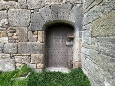 Ortaçağ Rosyth Şatosu 'nun taş duvarlarına yerleştirilmiş eski ahşap kapı, Forth Firth yakınlarındaki bir sanayi bölgesinde saklı.