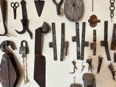 Beyaz bir duvara monte edilmiş antika eski aletler, kırsal işçilik ve zamansız tasarım sergiliyorlar. Tarih, onarım ve geleneksel el işi temaları için mükemmel..