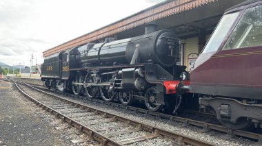 Aviemore tren istasyonu, bir yük treni ve buharlı bir lokomotifle modern seyahatle İskoçya 'nın tarihi cazibesini harmanlıyor..