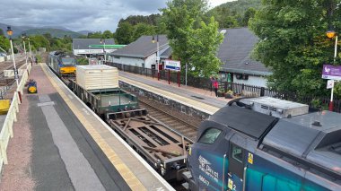 Aviemore tren istasyonu, bir yük treni ve buharlı bir lokomotifle modern seyahatle İskoçya 'nın tarihi cazibesini harmanlıyor..