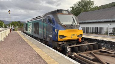 Aviemore tren istasyonu, bir yük treni ve buharlı bir lokomotifle modern seyahatle İskoçya 'nın tarihi cazibesini harmanlıyor..