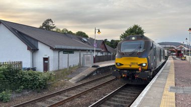 Aviemore tren istasyonu, bir yük treni ve buharlı bir lokomotifle modern seyahatle İskoçya 'nın tarihi cazibesini harmanlıyor..
