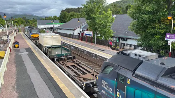 Aviemore tren istasyonu, bir yük treni ve buharlı bir lokomotifle modern seyahatle İskoçya 'nın tarihi cazibesini harmanlıyor..