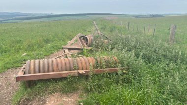Rusty abandoned farm rollers resting in overgrown grass, showing weathered metal and rural decay in the Scottish countryside.