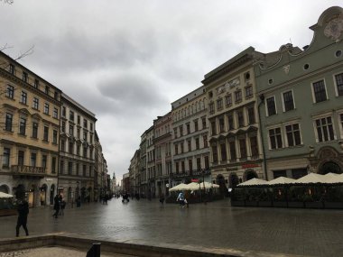 Krakws Rynek Gwny 'nin karamsar, yağmurlu manzarası, Cloth Hall, Town Hall Tower ve St. Marys Basilica' yı yansıtan titrek ıslak kaldırımları ortaya çıkarıyor.