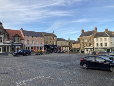 Eski manastır ve ortaçağ sokaklarının sonbahar ışığında yıkandığı tarihi Hexham market sahnesi.