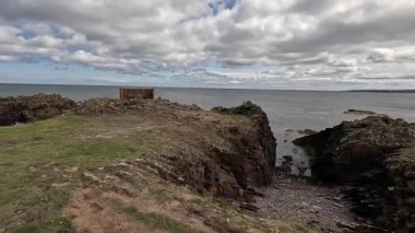 Doğu Lothian kıyısındaki St. Baldrick 's Cradle olarak bilinen kayalık çıkıntıyı geçerken dramatik uçurumlar, deniz ve antik volkanik oluşumlar görülür..