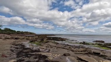 Tyne Sands boyunca yürümek, geniş kumlu kumsalları, deniz dalgalarını ve parlak bir yaz gününde kıyı manzarasını yakalamak.
