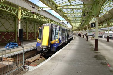 Wemyss Körfezi tren istasyonunun mimari harikası, cam çatılı salonu, eğri platformları, saat kulesi ve feribot bağlantısıyla atmosferik detaylarıyla yakalandı..