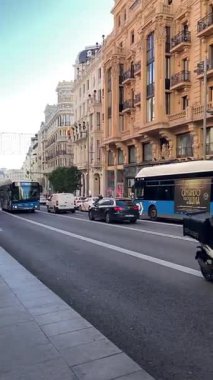 Açık yaz ışığı altında Madrid sokaklarında dolaşan otobüsler şehir ulaşımını ve şehir yaşamını yakalıyor.