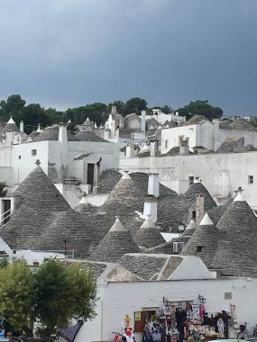 Alberobello 'nun ikonik beyazlatılmış trulli taştan çatıları, Apulian güneş ışığı ve tarihi cazibesi altında dar yollarda kümelenmiş.