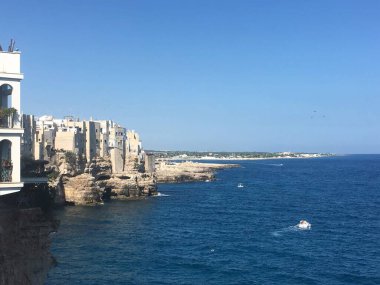 Polignano 'daki sahil kayalıkları berrak turkuaz suların üzerinde yükselen bir Mare, beyaz boyalı binalar parlak Akdeniz semaları altında kayalık yamaçlara yığılmış durumda. İtalya