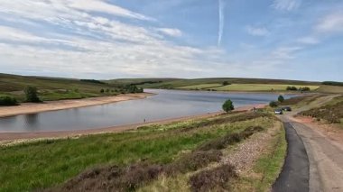 İskoç sınırlarındaki su rezervuarının yanında yürürken aynalı sular, bozkır bitkileri açık yaz gökyüzü altında çimenli kıyılar boyunca dolambaçlı yollar..