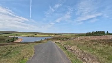 İskoç sınırlarındaki su rezervuarının yanında yürürken aynalı sular, bozkır bitkileri açık yaz gökyüzü altında çimenli kıyılar boyunca dolambaçlı yollar..