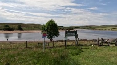 İskoç sınırlarındaki su rezervuarının yanında yürürken aynalı sular, bozkır bitkileri açık yaz gökyüzü altında çimenli kıyılar boyunca dolambaçlı yollar..