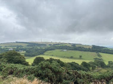 Batı Lothian tepeleri boyunca geniş açık panoramik manzaralar, yumuşak ışık altında uzak tepeler ile uçsuz bucaksız yaz gökyüzünün altında yumuşak kaygan kırlık ve tarım arazileri.