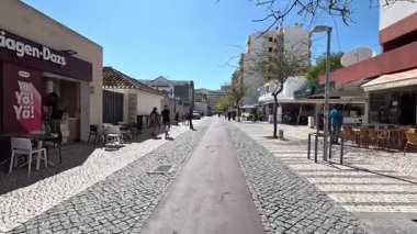 Portimo şehir merkezinde gezen sokak manzaraları, tarihi sessizlikleri, plazaları, kaldırım kafelerini, yaya yollarını ve nehir kıyısındaki kentsel yaşamı gösteriyor.