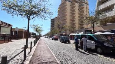 Portimo şehir merkezinde gezen sokak manzaraları, tarihi sessizlikleri, plazaları, kaldırım kafelerini, yaya yollarını ve nehir kıyısındaki kentsel yaşamı gösteriyor.