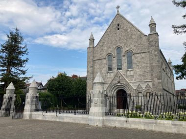 Cork şehir merkezindeki University College Cork kampüsünün dış görüntülerinde, gün ışığı altında tarihi akademik binalar yer alıyor.