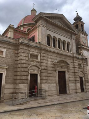 Fisano 'nun caddeleri, binaları ve anıtlarıyla canlı bir şehirde İtalyan mimarisi ve yerel kültürü sergileyen manzarası.