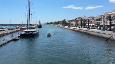 Portekiz 'deki Lagos limanı canlı marinalar, gezinti güvertesi, sakin sular ve kıyı atmosferiyle demirlenmiş tekneler.