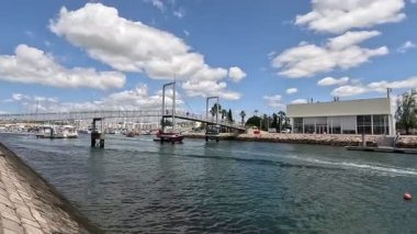 Portekiz 'deki Lagos limanı canlı marinalar, gezinti güvertesi, sakin sular ve kıyı atmosferiyle demirlenmiş tekneler.