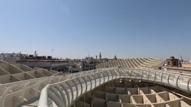 İspanya: Setas de Sevilla (Metropol Şemsiyesi) tepesinde yükseltilmiş yürüyüş yolu boyunca yürürken, sinsi ahşap şemsiyeler ve panoramik şehir manzaraları sergileniyor