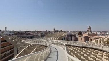 İspanya: Setas de Sevilla (Metropol Şemsiyesi) tepesinde yükseltilmiş yürüyüş yolu boyunca yürürken, sinsi ahşap şemsiyeler ve panoramik şehir manzaraları sergileniyor