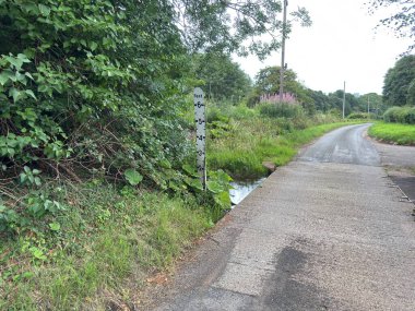 İskoçya 'nın kırsal kesimlerinde su seviyesi düşük sığ bir dere boyunca akan bir ırmak, sınır yüzeyini su altında bırakmak yerine açıkta bırakıyor..