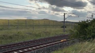 İskoçya: Modern İngiliz yolcu trenleri Doğu Lothian, İskoçya 'dan hızla geçerek demiryolu altyapısı ve manzaralı kırsal manzaralar sergiliyor.