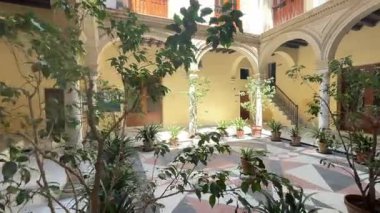 Courtyard set within the historic centre of El Puerto de Santa Maria, Spain, showing arcaded galleries, tile floors, white walls, and open central space