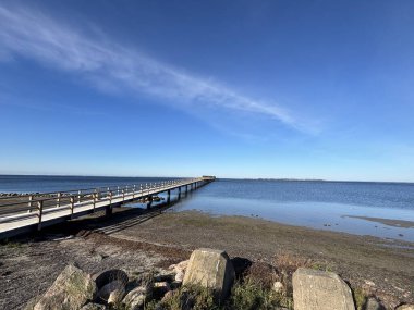 Bright sunlight on Landskrona Sweden coastal area featuring Oresund strait horizon sandy beach and gentle waves with clear weather conditions.