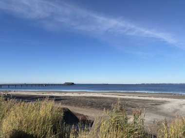 Bright sunlight on Landskrona Sweden coastal area featuring Oresund strait horizon sandy beach and gentle waves with clear weather conditions.