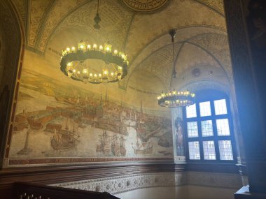 Grand halls and staircases inside Copenhagen City Hall Denmark showcasing ornate decorations stained-glass panels mosaic floors and the intricate Jens Olsen World Clock mechanism amid municipal council spaces.
