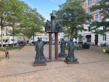 Jens Galschit Red Dante installation with three red pig figures on Dantes Plads Copenhagen Denmark opposing Q-Park underground parking near Glyptotek museum.