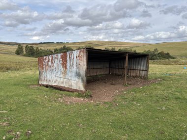 İskoç sınırlarındaki sığırlar için harap olmuş metal ahır yıpranmış demir levhalar, sarkık çelik yapılar, enkaz yığınları, bitişik taş duvarlar, koyun tarlaları ve bulutlu gökyüzü altındaki uzak bozkırlar..