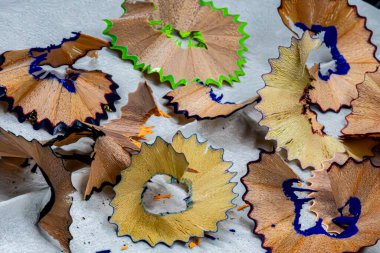 Yeşil ve mavi renkli bir yığın kalem talaşı. Yığın beyaz bir yüzeyde.