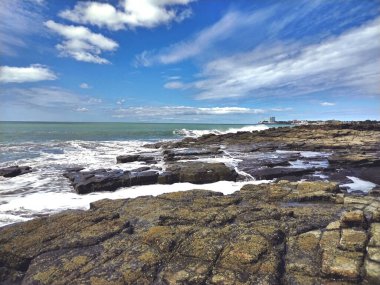 Deniz kenarındaki kayalık bir körfezin güzel manzarası. Bulutlu bir gökyüzünün altında kayalıklara vuran dalgalar. Nueva Gorgona, Chame, Panama.