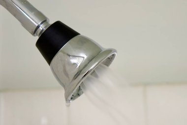 Metal bir duş başlığından akan su yumuşak bir dere oluşturur.