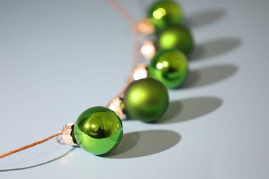 a row of green christmas ornaments on a blue background, casting shadows