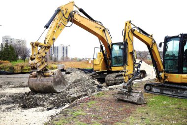 Sarı kazıcılar şehir binalarının zeminine karşı bir inşaat alanında çalışıyorlar..