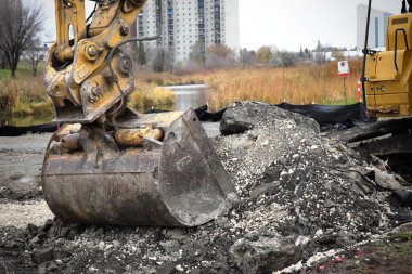 Sarı kazıcılar şehir binalarının zeminine karşı bir inşaat alanında çalışıyorlar..