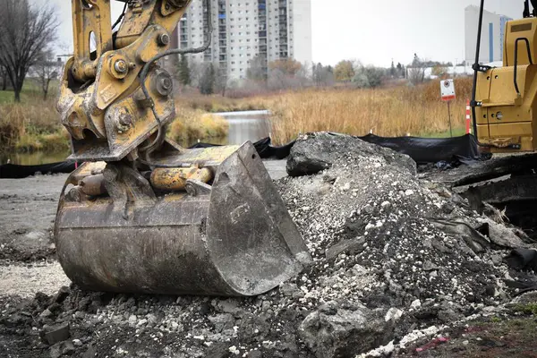 Sarı kazıcılar şehir binalarının zeminine karşı bir inşaat alanında çalışıyorlar..