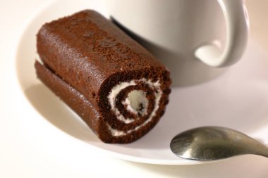 Beyaz bir tabakta servis edilen kremalı çikolatalı rulo..