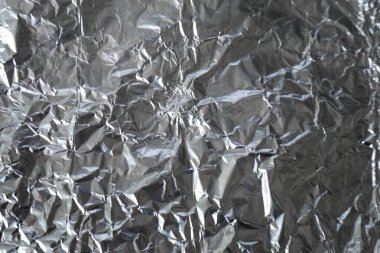 Buruşuk alüminyum folyo yüzeyi karakteristik parlaklık ve kırışıklıklarla.