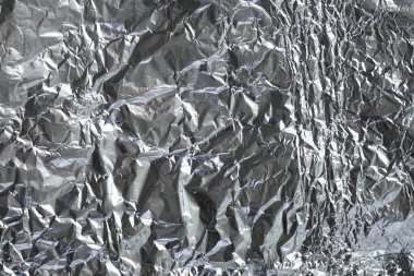Buruşuk alüminyum folyo yüzeyi karakteristik parlaklık ve kırışıklıklarla.