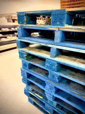 blue wooden pallets stacked in a store with shelves and products in the background. clipart