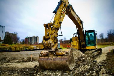 Sarı kazıcılar şehir binalarının zeminine karşı bir inşaat alanında çalışıyorlar..