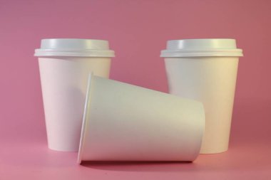 Pembe arka planda kapağı olan tek kullanımlık bir kağıt bardak. Paket içecekler için minimalist bir tasarım içeriyor..